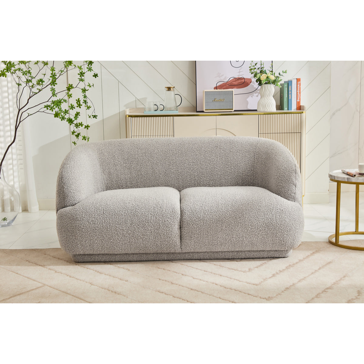 The Avriio Madrid 2 Seater Taupe Sofa is featured in a chic living room with a beige cabinet, decor accents, and a round side table. Enjoy seamless setup with home delivery and white glove service options.