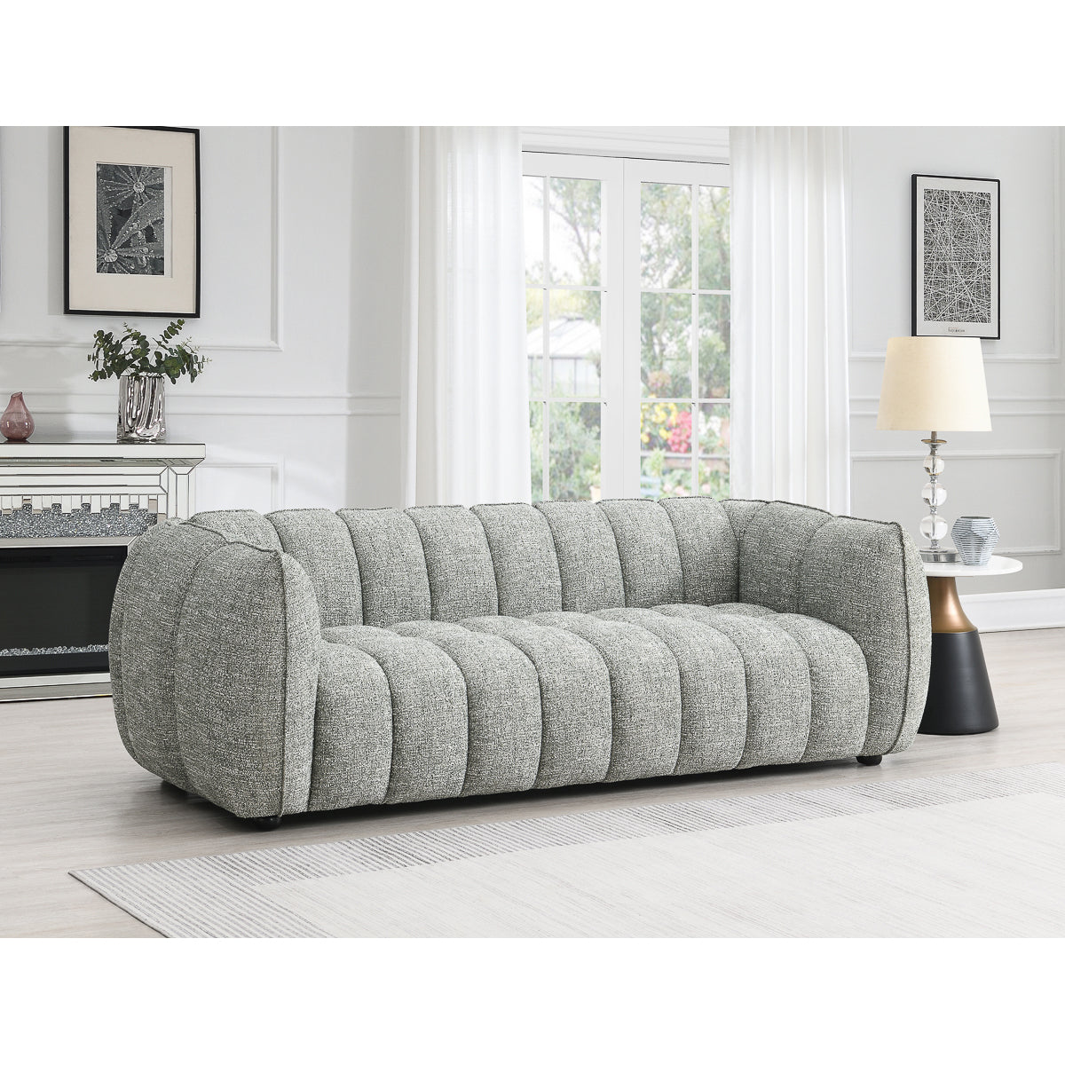 
                  
                    A modern living room features the Avriio Vienna Fluted 3 Seater Winter Moss Fabric Sofa at the center, with a floor lamp right, fireplace and art left, and large windows with white curtains—home delivery/white glove available.
                  
                
